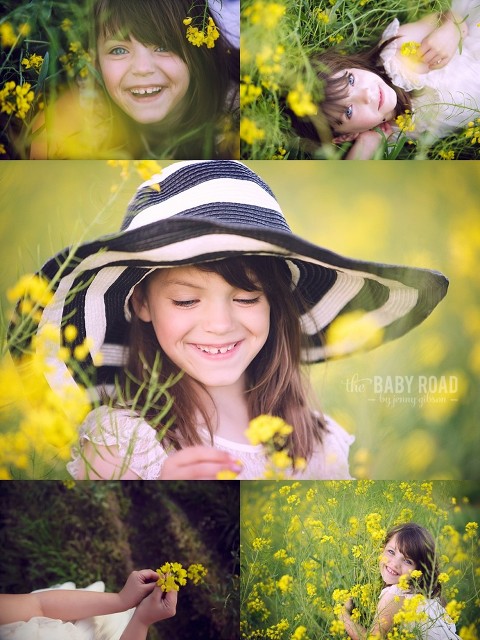 blue eyed little girl laying in yellow flowers, holding flowers and wearing a striped hat