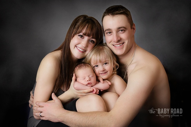 family of 4 and newborn on grey background